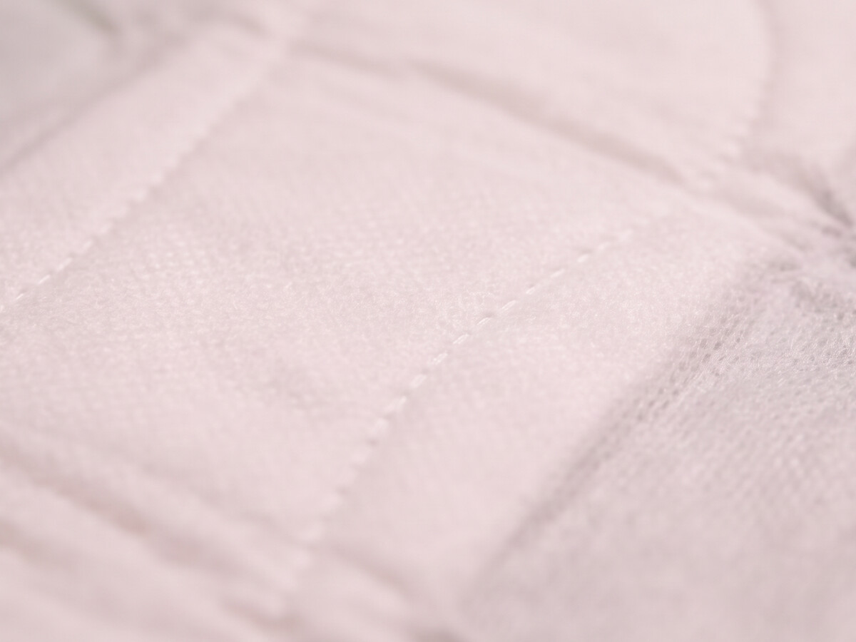 Extreme macro of a pad top sheet, its woven texture and quilted stitching